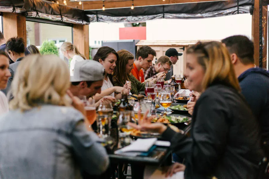 Junge Menschen freuen sich auf einer Veranstaltung beim Essen am Tisch